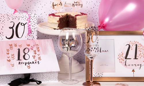 gifts for special birthdays arranged including a picture frame, wine glass, gift box, cake and balloon. 